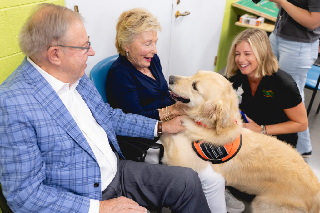 Seniors smiling with a therapy dog during a heartwarming visit.