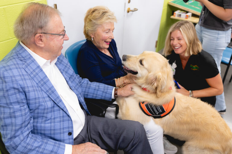 Seniors smiling with a therapy dog during a heartwarming visit.