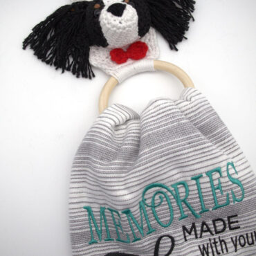Crochet dog towel holder with embroidered text Memories made with your dog on striped fabric background.
