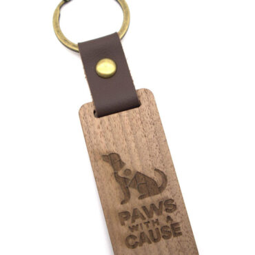 Wooden keychain with Paws with a Cause logo, featuring a dog silhouette. Perfect for pet lovers and charity support.