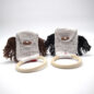Crocheted baby teething rings with handles and tassels, in white, brown, and black yarn, on a white background.
