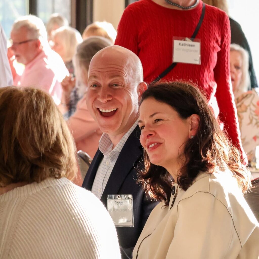 Group of people enjoying a social event, smiling and interacting warmly with each other in a lively setting.
